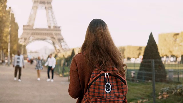 在法国巴黎的埃菲尔铁塔附近背着背包的年轻女子的背影。游客欣赏风景视频素材