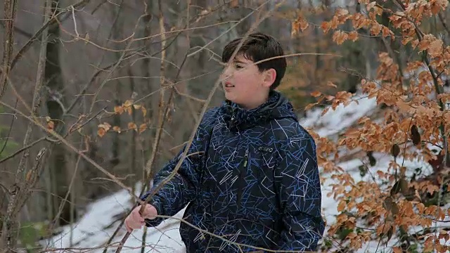 森林里的男孩。雪地里的脚步声。蓝色裤子，棕色头发。害怕和孤独视频素材