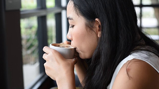 美丽的亚洲年轻女子喝咖啡视频素材