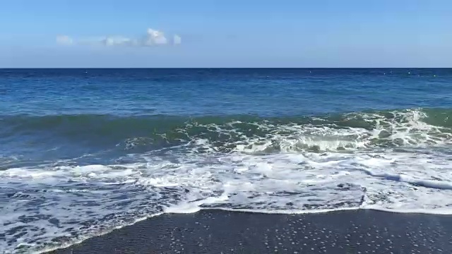 浪涛拍打着海岸，激起浪花希腊,圣托里尼岛岛。佩里萨海滩黑色火山沙视频素材