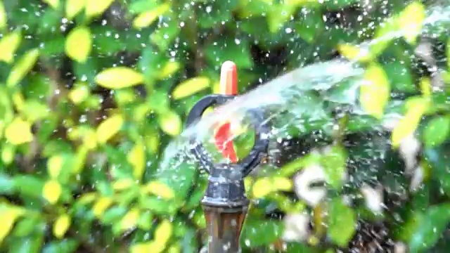 慢动作洒水车旋转浇水流在花园早上视频素材