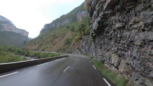 在法国，骑摩托车的人在风景山岩路上行驶。多雨的天气。第一个人的观点视频素材