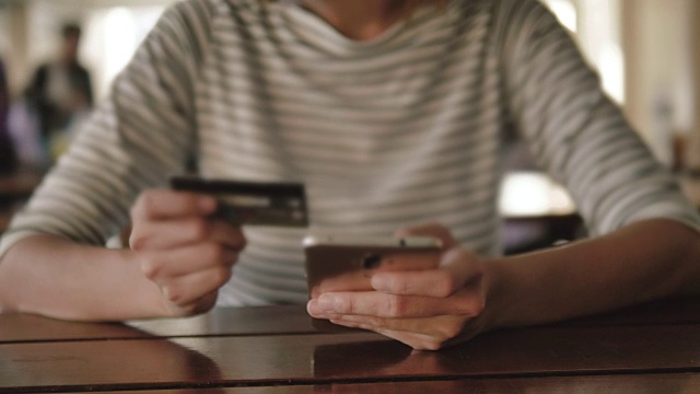 年轻的亚洲女人用信用卡在手机上购物视频素材