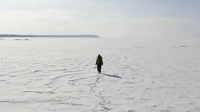 一个女人在冬天走在结冰的海湾上视频素材