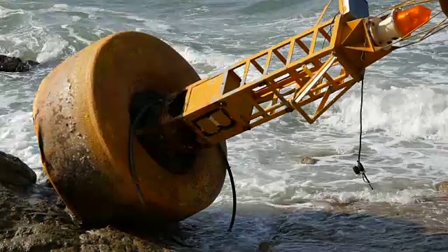 湛蓝的海岸上的黄色大浮标。海浪拍打着浮标视频素材