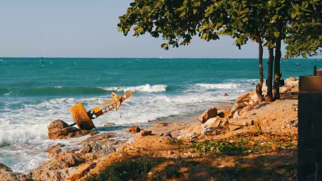 湛蓝的海岸上的黄色大浮标。海浪拍打着浮标和岸边的大岩石视频素材