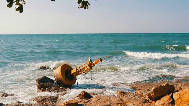 湛蓝的海岸上的黄色大浮标。海浪拍打着浮标和岸边的大岩石视频素材