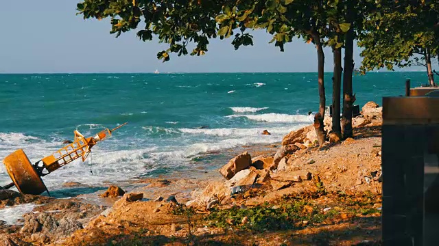 湛蓝的海岸上的黄色大浮标。海浪拍打着浮标和岸边的大岩石视频素材