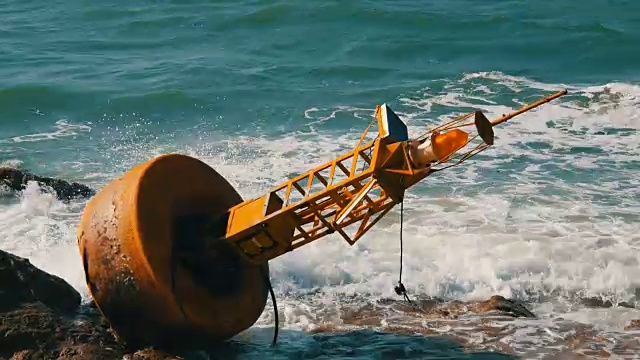 湛蓝的海岸上的黄色大浮标。海浪拍打着浮标和岸边的大岩石视频素材