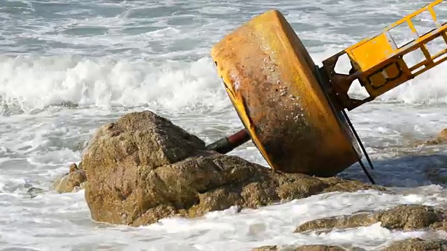 湛蓝的海岸上的黄色大浮标。海浪拍打着浮标和岸边的大岩石视频素材