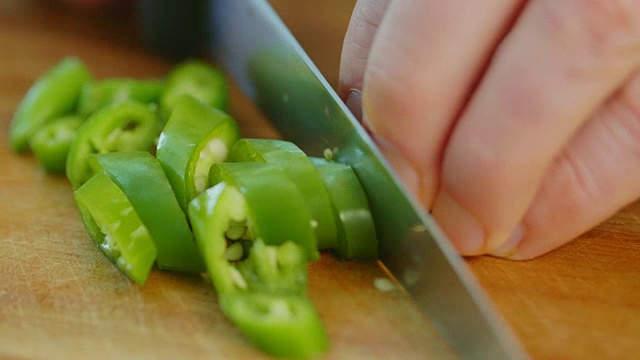 一名男子在厨房的砧板上切绿辣椒视频素材