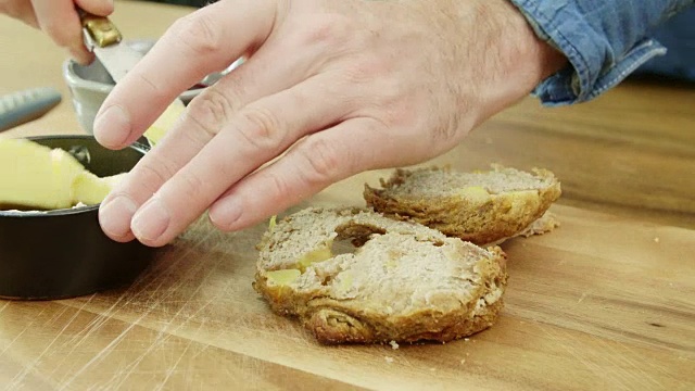 男人的手在切烤饼和用刀抹黄油视频素材