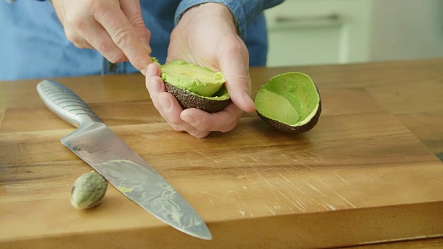 男人用勺子取出牛油果果肉的手视频素材