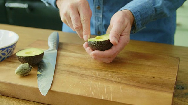 男人的手切割并取出鳄梨果肉视频素材