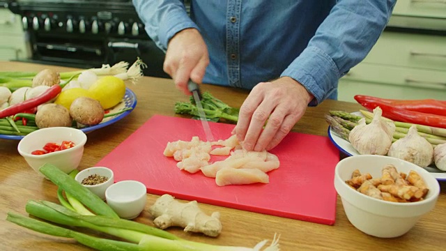 男人的手在切菜板上切生鸡肉的特写视频素材