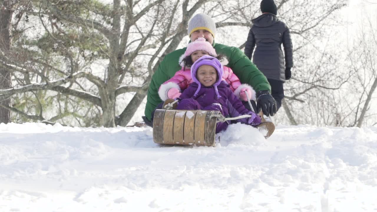 爸爸和孩子们一起滑雪橇视频素材