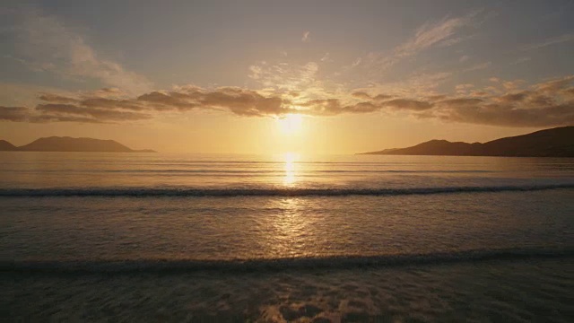 日落时海浪向海滩移动的航拍图视频素材