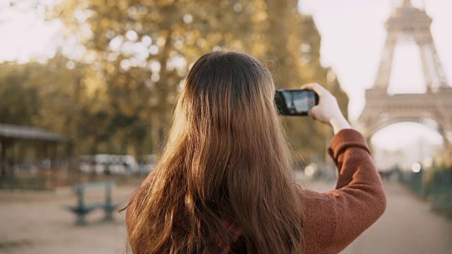 年轻女子用智能手机拍照的后视图。十几岁的游客在法国巴黎探索艾菲尔铁塔视频素材