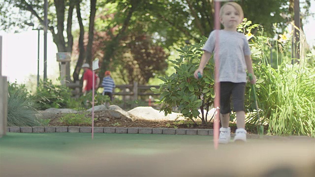 小孩子在高尔夫球场上用高尔夫球杆击打地面视频素材