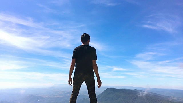 一个人站在山上，手臂举得很慢。蓝天和白云视频素材