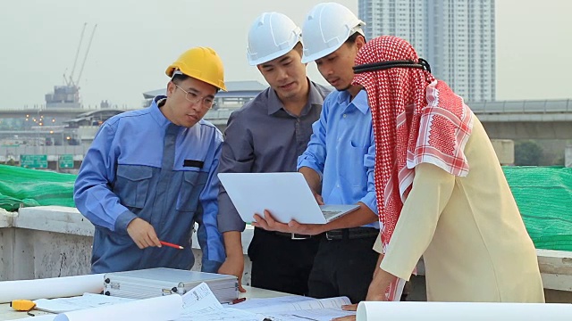 亚洲工程师和阿拉伯人在工地上检查图纸，谈论建设项目视频素材