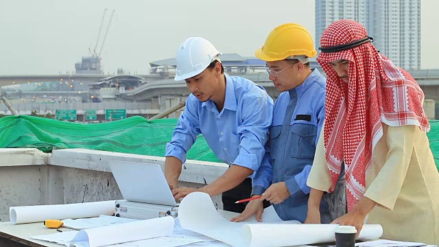 亚洲工程师和阿拉伯人在工地上检查图纸，谈论建设项目视频素材