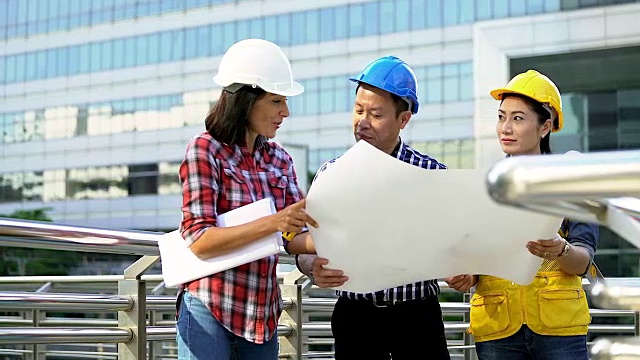 工程师们在建筑工地开会。同事讨论。老板和员工争吵。在团队的对话。戴上头盔拿纸上的计划。视频素材