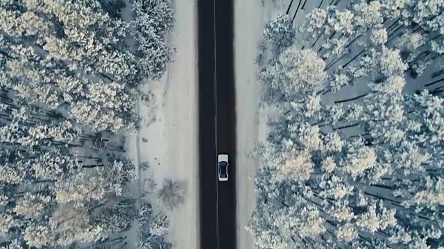 雪地里的汽车行驶在冬日的乡村道路上。鸟瞰图。4 k。视频素材