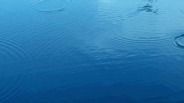 雨季近距离降雨水滴落在河面的蓝色调，4K Dci分辨率视频素材