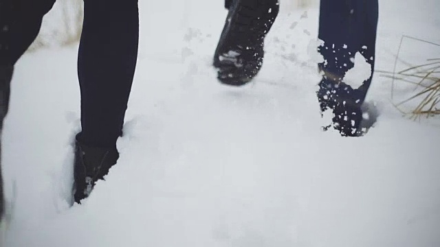 一个男人和一个女人在雪地上走过。卡压在雪堆上。稳定的拍摄视频素材