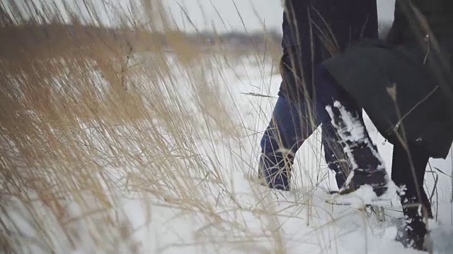 一个男人和一个女人在雪地上走过。卡压在雪堆上。稳定的拍摄视频素材