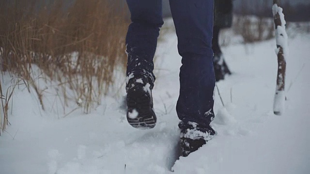 一个男人和一个女人在雪地上走过。卡压在雪堆上。稳定的拍摄视频素材