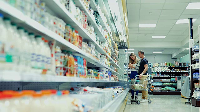 guy and girl choose products in the supermarket / Couple in supermarket /年轻夫妇在超市购物视频素材