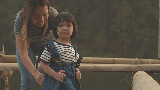 一个女人和一个小女孩坐在山河边视频素材