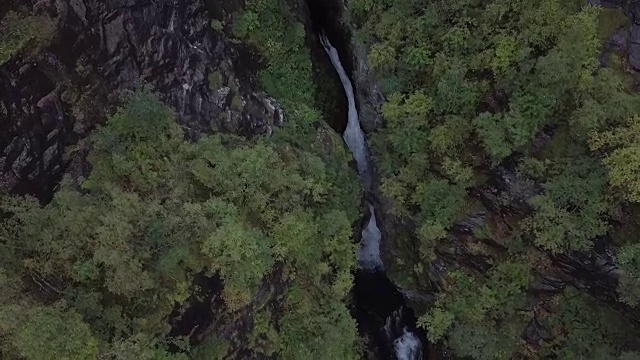 4K鸟瞰图激流瀑布通过深史诗山谷的岩石和森林视频素材