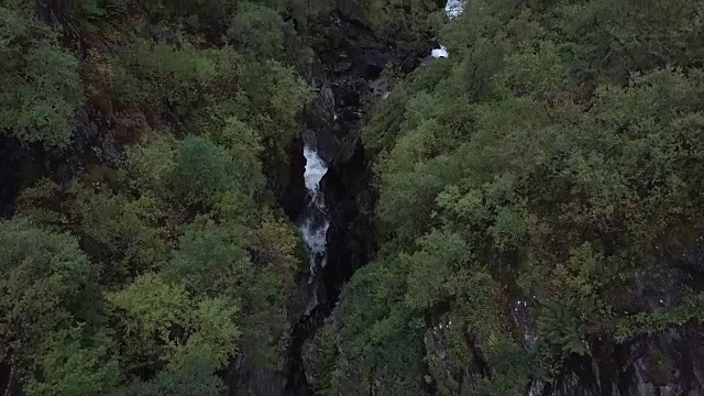 4K鸟瞰图激流瀑布通过深史诗山谷的岩石和森林视频素材