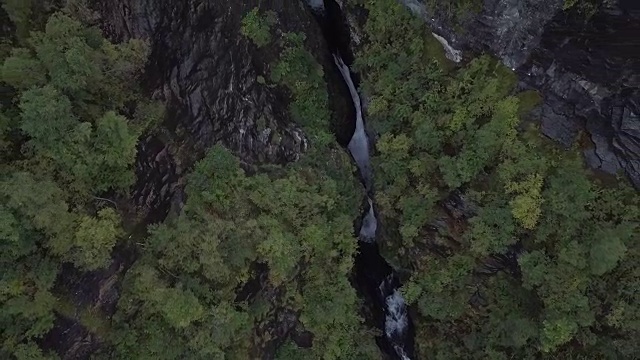 4K鸟瞰图激流瀑布通过深史诗山谷的岩石和森林视频素材