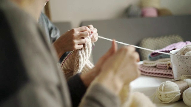 近距离女性的手编织羊毛衣服。两个女人在织衣服视频素材