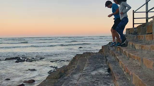 一对活跃的夫妇在日出时在海滩边的台阶上锻炼视频素材