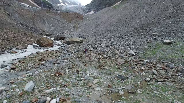 一个女人带着一只狗沿着峡谷走向冰川视频素材