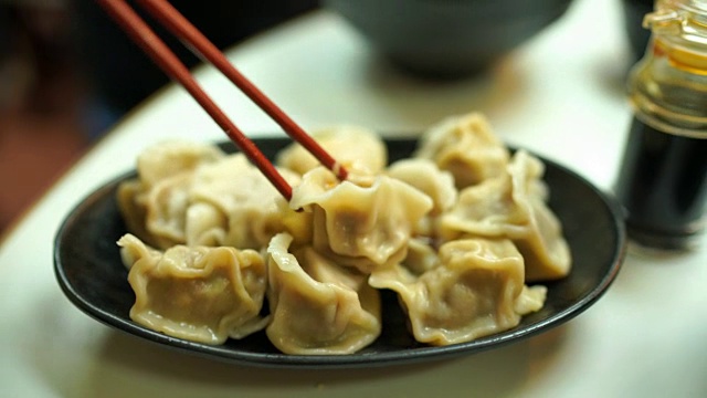 男子在中餐馆吃香港热馄饨或饺子的照片视频素材