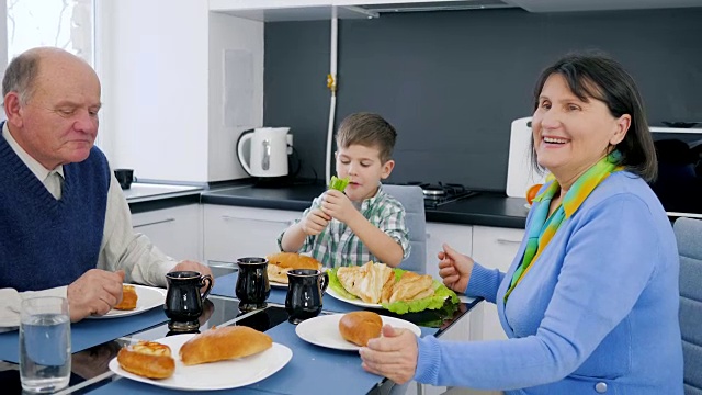 老人、小孩和爷爷奶奶在厨房里吃烘焙食品视频素材