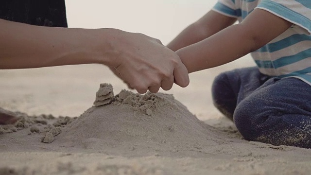 年轻的母亲和小男孩在沙滩上玩沙子视频素材