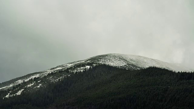 时间流逝，雷云移动上方的冬季山脉，暗松林前景自然景观视频素材