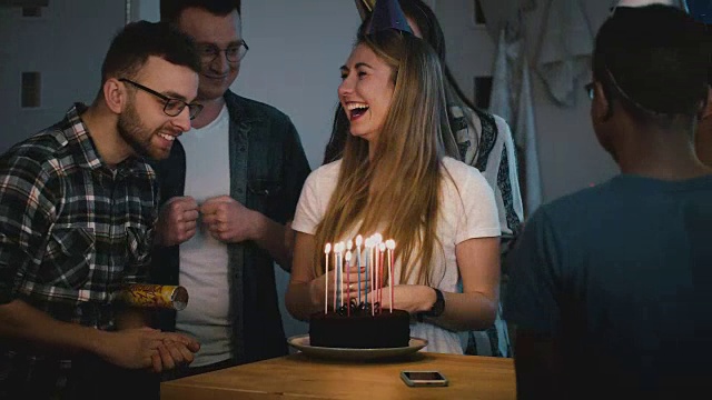 漂亮的白人女孩拿着生日蛋糕微笑。多民族朋友戴着有趣的帽子一起庆祝，拥抱幸福。4 k视频素材