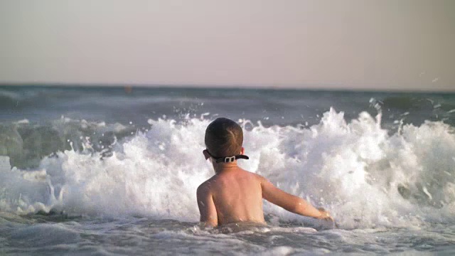 孩子在海里洗澡，海浪打到了他视频素材