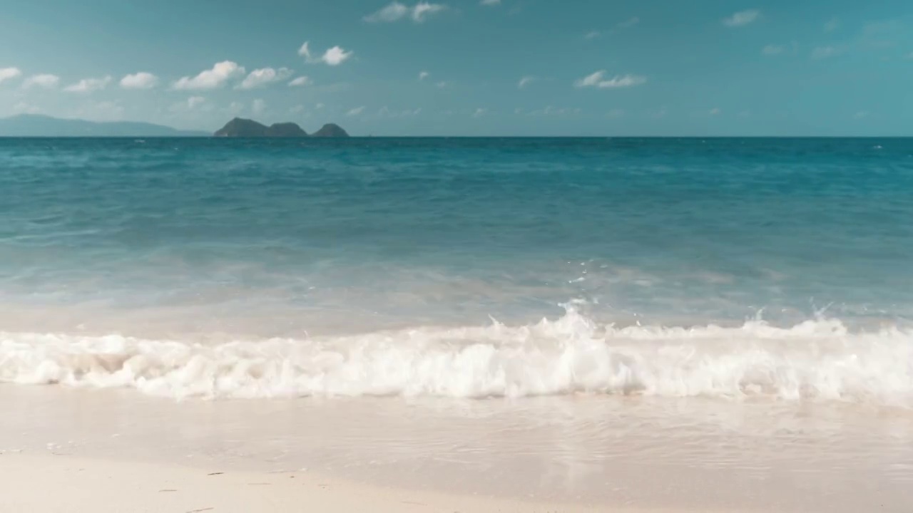 海滩上的波浪，地平线上的岛屿视频素材