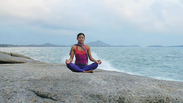 和谐的女人坐在土耳其姿势苏哈萨纳石质海滩视频素材