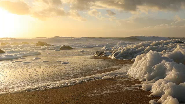 日落时海浪在海滩上激起泡沫视频素材