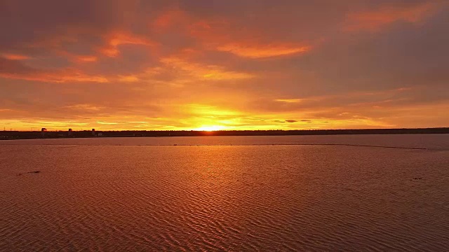 在血淋淋的夕阳下，在湖面上空飞翔视频素材